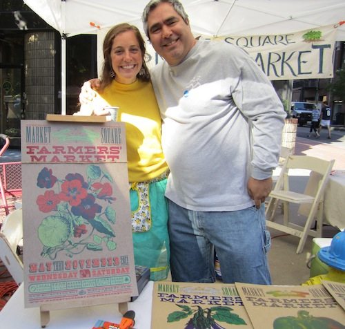Kimberly Pettigrew and Art Carmichael staff the Market Square Farmers' Market booth. That's this year's poster on the left.