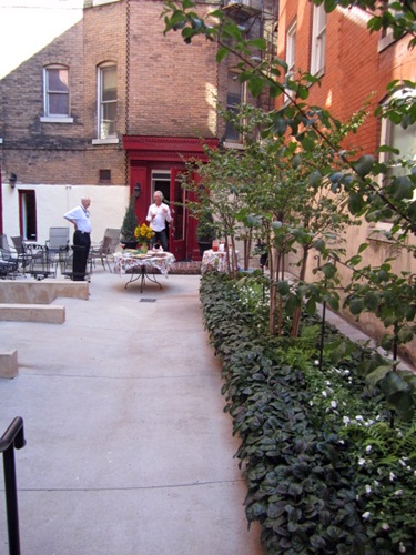 our-courtyard Here is our courtyard. Way at the end are Alan and our neighbor Stuart Morrison, who actually lives in the Cunningham (with the maroon door). Stuart and his wife, Lisa, planted the pretty garden.