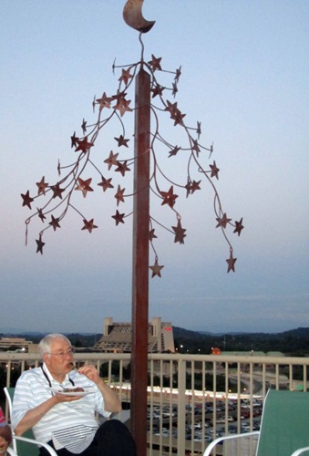 roof-sculture Alan Carmichael munches a tiny lamb lollipop at sunset under a stunning sculpture on Tim Young's rooftop at The Gallery condos.