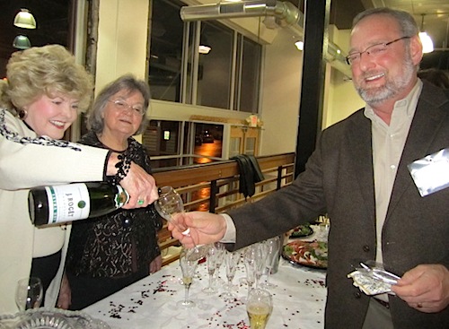 pouring Host Charlene Edwards pours a glass of champagne for KSO Board member Tom Shaw and Pat Jobe, another event host, looks on.