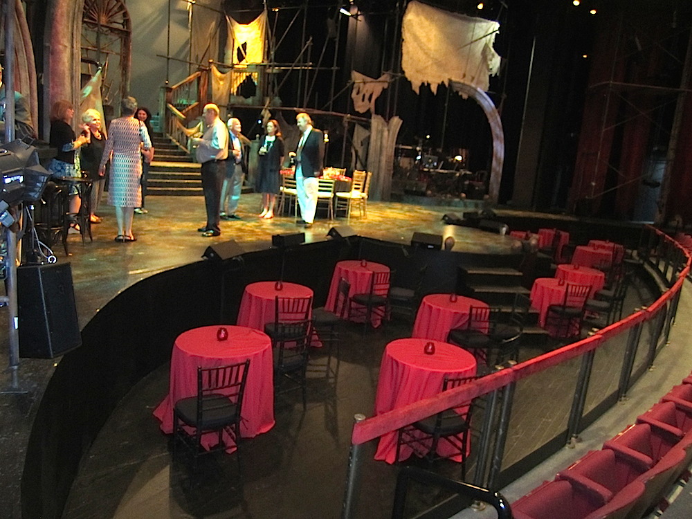 The setting is a dilapidated theater where a group of actors are planning to produce the play. It's a play within a play. Some lucky audience members got to sit at those cocktail tables during the show.