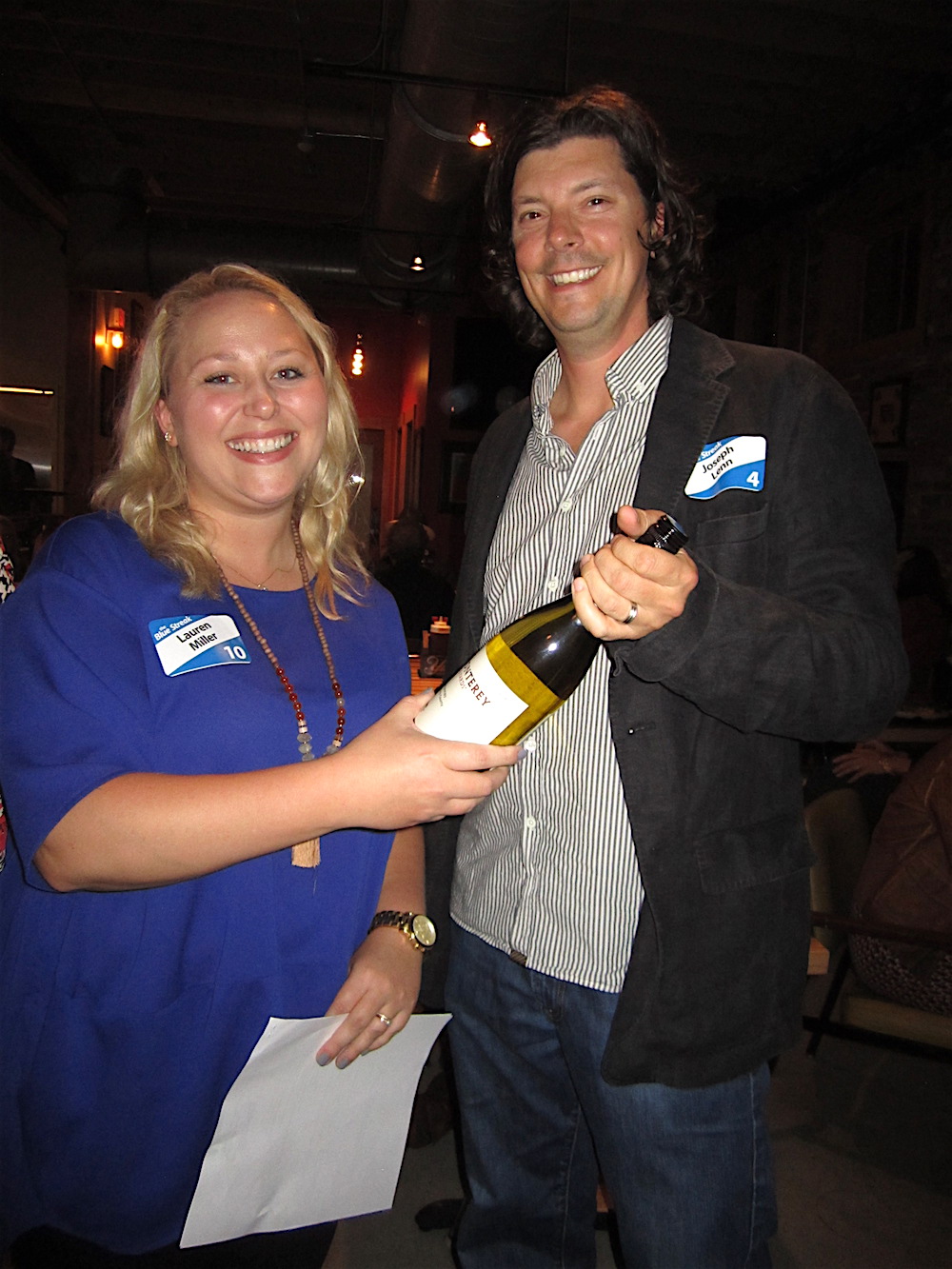 Moxley Carmichael's Lauren Miller awards to booby prize -- a bottle of chardonnay -- to Chef Joseph Lenn, who came in last place in the pop quiz. (He's still a winner in our book, though!)
