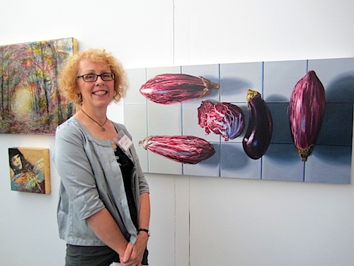 eggplants This stunning oil on canvas caught my attention from across the room. At 24" by 48," it would look great in a large kitchen. (Unfortunately, I have a tiny kitchen!) Here is Knoxville artist Denise Stewart-Sanabria beside her work, "Surrounded by Eggplants."