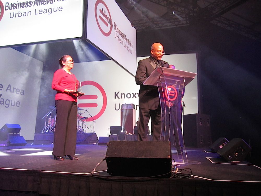 Urban League Board Member Rosa Mar holds the Minority Business Award as Mark Deathridge, president of CEO of East Tennessee Mechanical Contractors, delivers his acceptance speech.