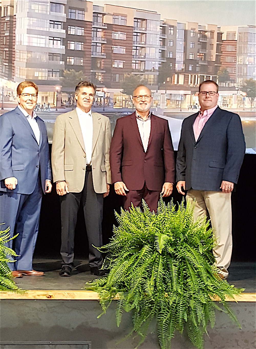 Developers of Regas Square, from left, Joe Petre, Thomas Wolf, Matt Hasbrouck and Doug White stand before a rendering of the new development.