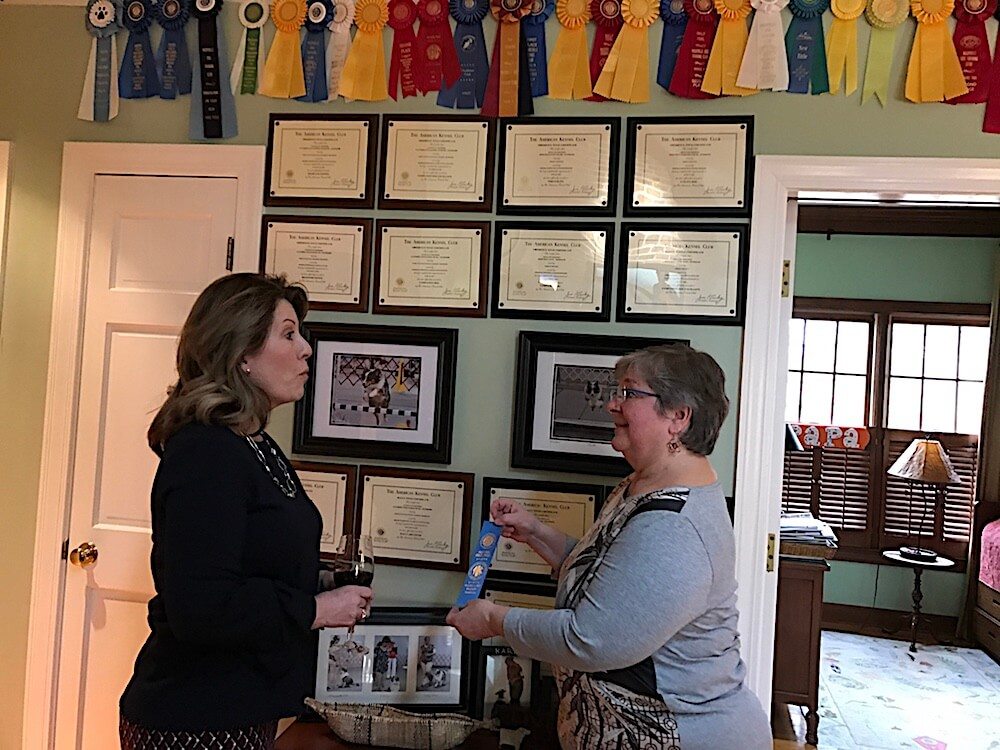 Deb DiPietro, right, showing Polly Fisher the latest ribbons her dogs have secured. Look above their heads!